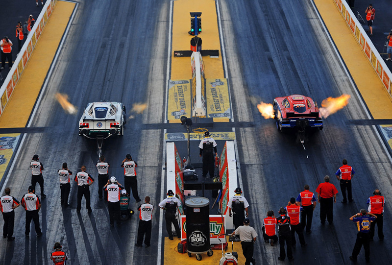 Pit Crew behind two race cars at starting line